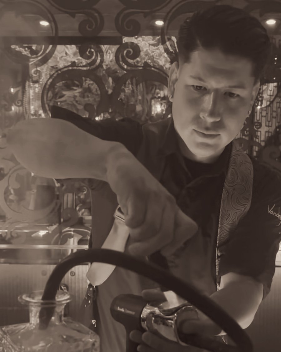 Angelo Palomino smoking a cocktail behind the bar